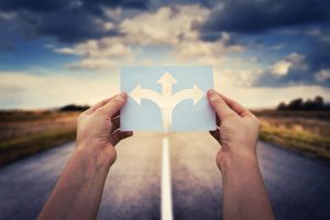Hands holding paper with arrows crossroad symbol split in three different directions. Difficult life transitions and big life changes need counsel. Meet with a skilled therapist in Tigard, OR 97223