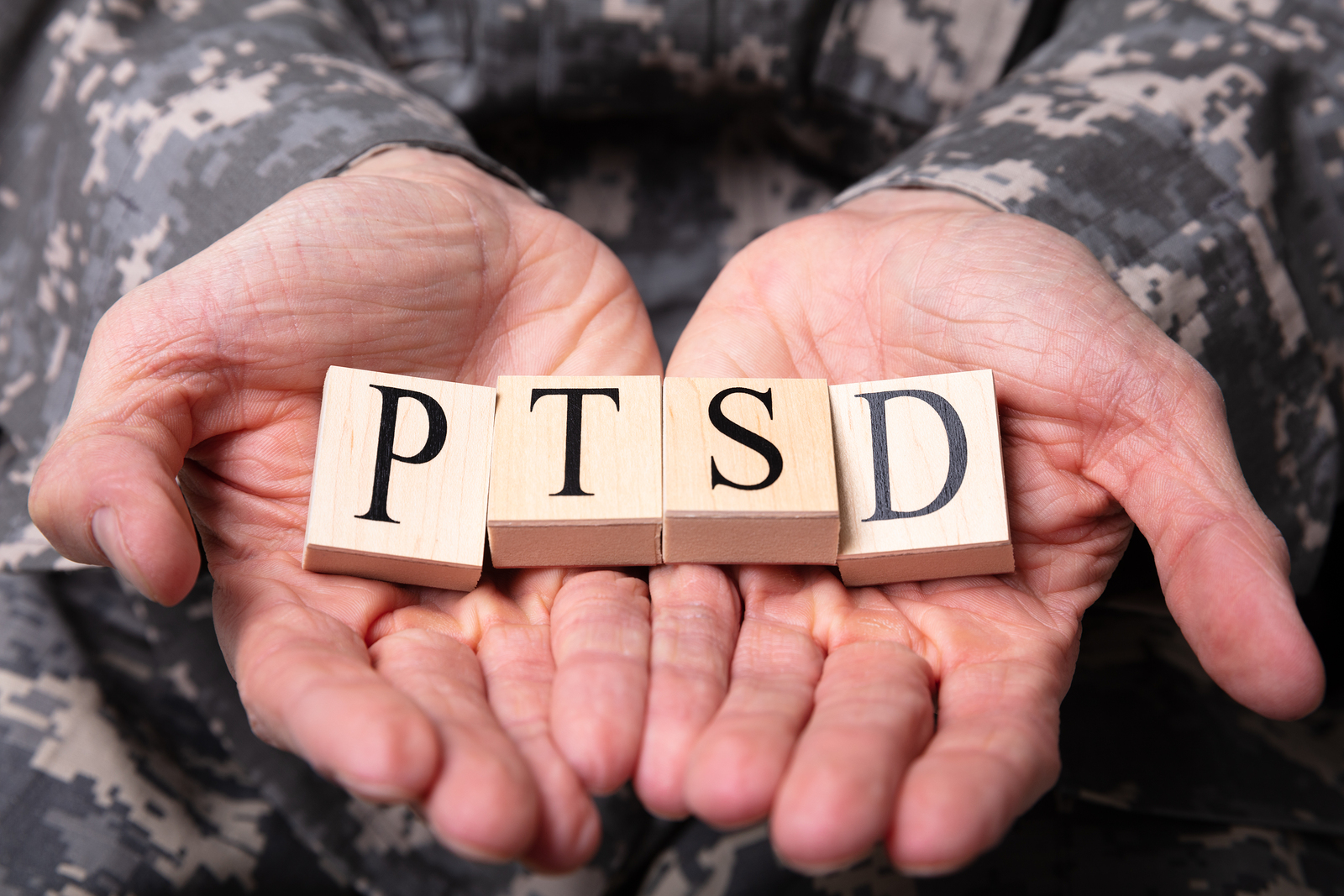 Close up of military service member's hands holding tiles with the letters PTSD on them. People suffer from PTSD and childhood neglect can benefit from trauma therapy in Tigard, OR. If you live in the Portland area and are suffering from PTSD symptoms, consider calling Discover Counseling.