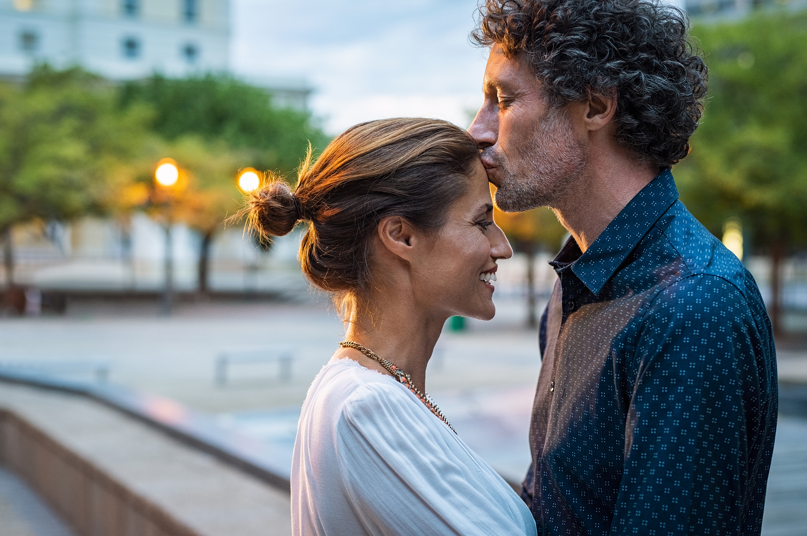 Man kissing his wife's head on the street after connecting through marriage counseling in Tigard, OR  from a marriage and family therapist in the Portland area